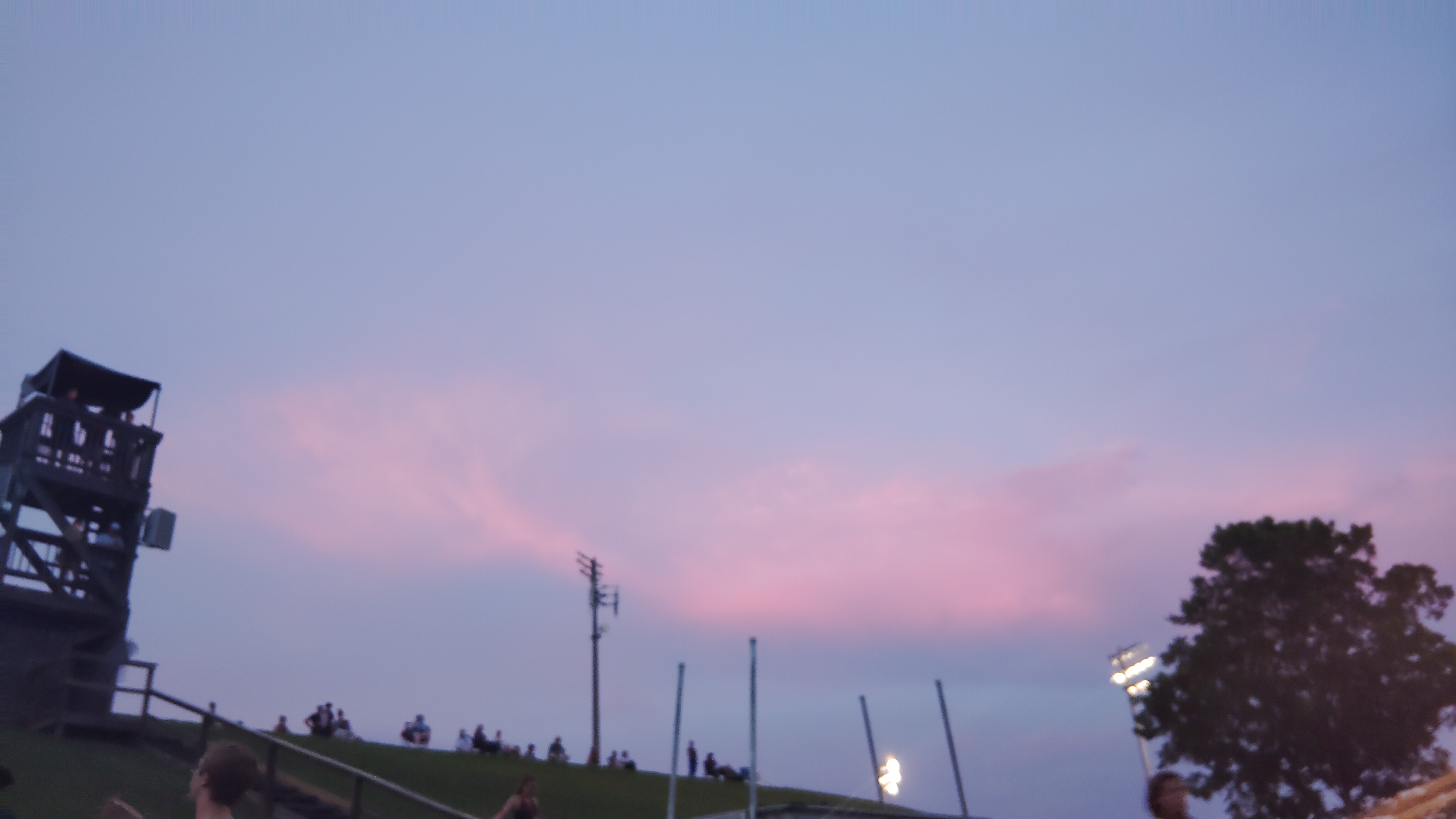 A pink sunset with a wooden tower in the foreground